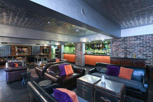 a bar with leather couches and a bar with a bartender at Rydges Armidale in Armidale