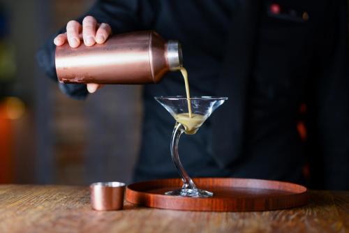 a drink being poured into a martini glass on a table at Rydges Armidale in Armidale