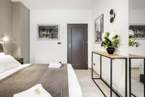 a white bedroom with a large bed and a desk at Apartamenty L11, Limanowskiego in Poznań