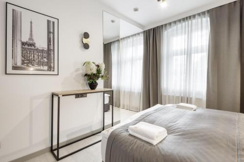 a white bedroom with a bed and a window at Apartamenty L11, Limanowskiego in Poznań