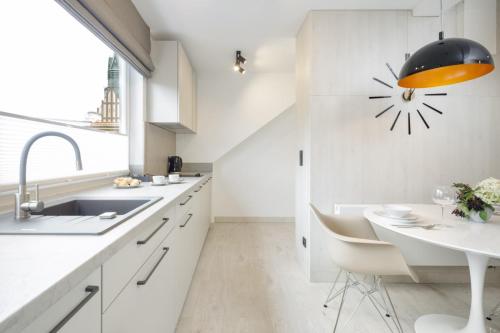 a kitchen with white cabinets and a sink and a clock on the wall at Apartamenty L11, Limanowskiego in Poznań