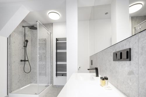 a white bathroom with a shower and a sink at Apartamenty L11, Limanowskiego in Poznań