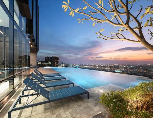 uma piscina no topo de um edifício com vista para uma cidade em The Quarter Ari by UHG em Bangkok
