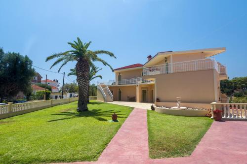 una casa con una palma e un vialetto rosa di Makis studios a Skala di Cefalonia