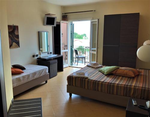 a bedroom with two beds and a desk and a balcony at Cerri Hotel in Castellammare del Golfo