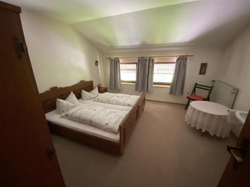 Schlafzimmer mit einem Bett, einem Tisch und einem Fenster in der Unterkunft Gästehaus Buchinger in Bayerisch Eisenstein