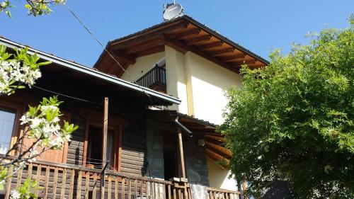 a wooden house with a porch and a tree at Family Apartments Le Chalet in Champoluc