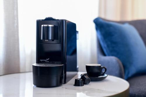 a coffee maker sitting on a table next to a coffee cup at Powerhouse Hotel Tamworth by Rydges in Tamworth