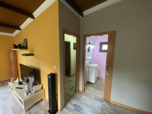 a living room with a tv and a doorway at Casa rural O CARBALLO DA PEDRA in La Cañiza