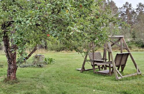 two chairs sitting on a swing under an apple tree at Solvillan in Korppoo