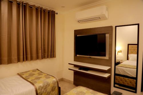 a hotel room with a bed and a tv and a mirror at Wongdhen House in New Delhi