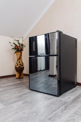 a black refrigerator sitting on the floor with a vase at Гостинний двір "Марія" in Kropyvnytskyi