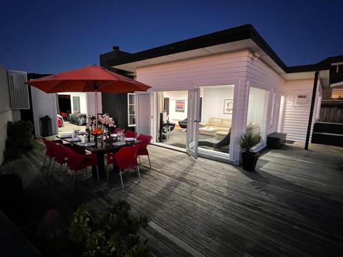 a wooden deck with a table and an umbrella at Ocean Front East End Beach House in New Plymouth