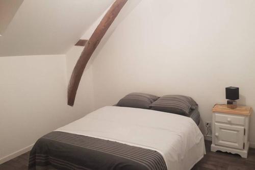 1 dormitorio con cama y pared blanca en Maison de bourg avec extérieur., en Grez-en-Bouère