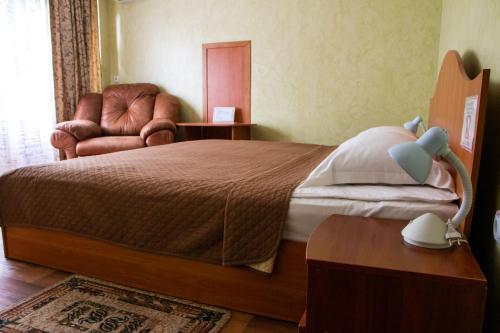 a bedroom with a large bed and a chair at Гостинний двір "Марія" in Kropyvnytskyi