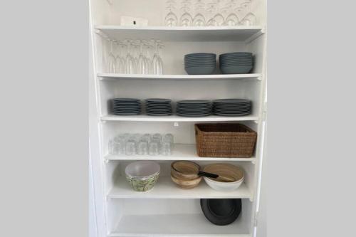 un garde-manger blanc avec assiettes et vaisselle sur étagères dans l'établissement Agon-Coutainville, villa bord de mer, à Agon-Coutainville