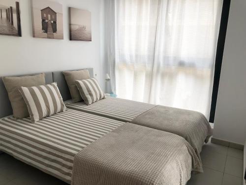 Una cama grande en un dormitorio con ventana. en Calpe Beach II - sea & pool view apartment, en Calpe