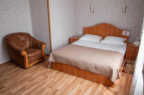 a bedroom with a bed and a chair at Гостинний двір "Марія" in Kropyvnytskyi