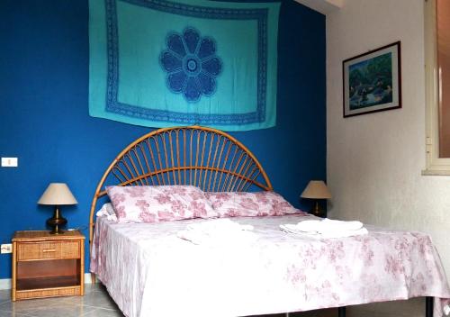 sypialnia z łóżkiem z niebieską ścianą w obiekcie Casa vacanza in villa con piscina! w mieście Triscina