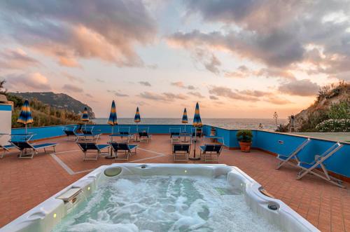 a hot tub on a patio next to the ocean at Hotel Cava Dell'Isola in Ischia