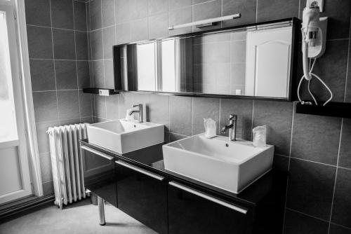 a bathroom with two sinks and a mirror and a radiator at Logis Le Saint Hubert in Haybes