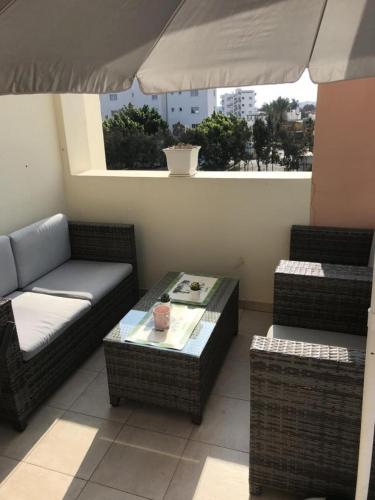 eine Terrasse mit einem Sofa, einem Tisch und einem Sonnenschirm in der Unterkunft Protaras, Janas apartment in Protaras
