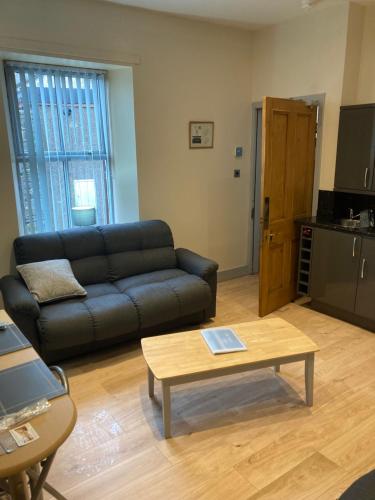 a living room with a black couch and a coffee table at The Annex Keith Self Catering WiFi Private Parking bkng in Keith