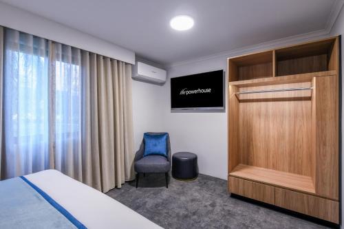 a bedroom with a bed and a chair and a television at Powerhouse Hotel Tamworth by Rydges in Tamworth