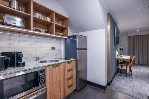 a kitchen with a sink and a refrigerator at Powerhouse Hotel Tamworth by Rydges in Tamworth