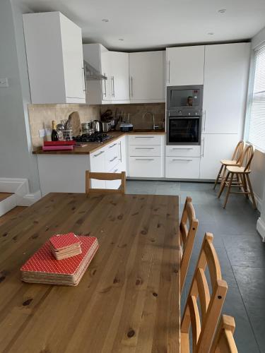 a kitchen with white cabinets and a wooden floor at Wonderful Home and parking, pets allowed in Tenby