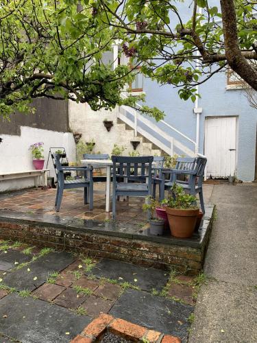 a patio with two benches and a table and some plants at Wonderful Home and parking, pets allowed in Tenby