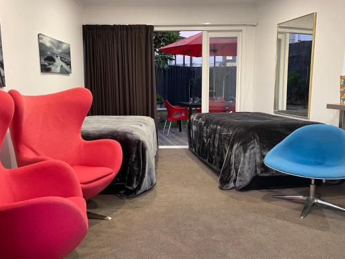 a bedroom with a bed and a chair and a table at Ocean Front East End Beach House in New Plymouth