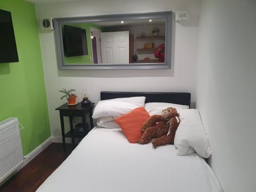un osito de peluche sentado en una cama en un dormitorio en Anerley-Crystal Palace, en Sydenham