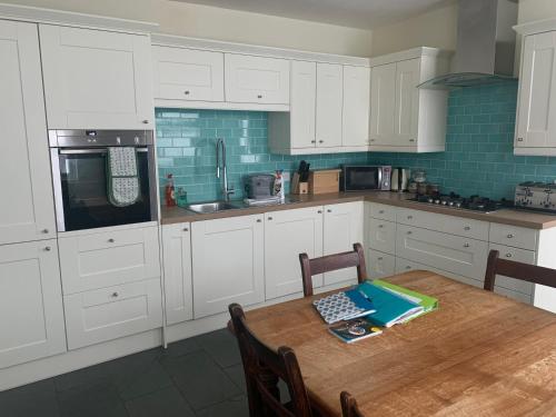 a kitchen with white cabinets and a wooden table at Beautiful Tenby House, pets allowed in Tenby
