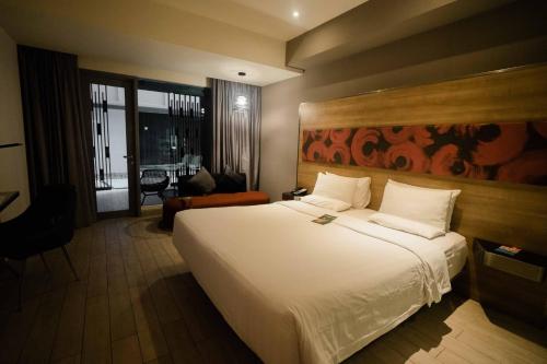 a hotel room with a large white bed and a chair at Novotel Pekanbaru in Pekanbaru