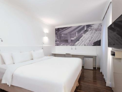 a hotel room with a white bed and white walls at Mercure Sao Paulo Paulista in São Paulo