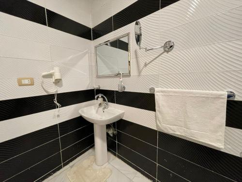 Kemet Apartment luxor في الأقصر: حمام أسود وبيض مع حوض ومرآة
