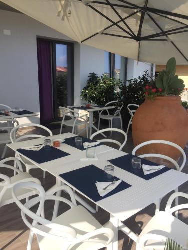 a table with white chairs and a large vase at B&B Maria in Gioia Tauro