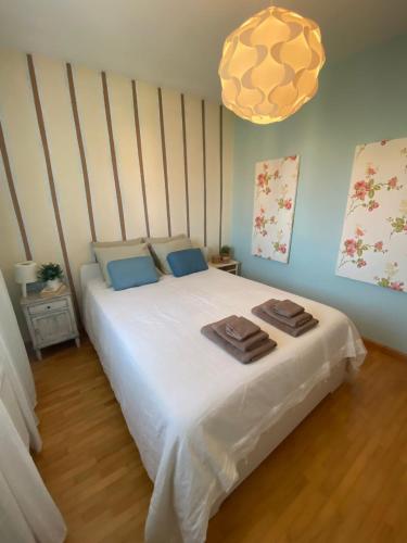 a bedroom with a white bed with towels on it at Lar Toxiño in Ourense