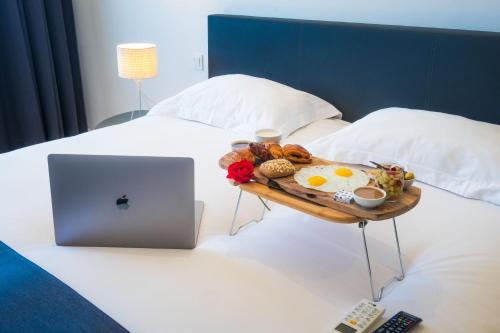 a tray of breakfast foods on a bed with a laptop at Asilah 32 in Asilah