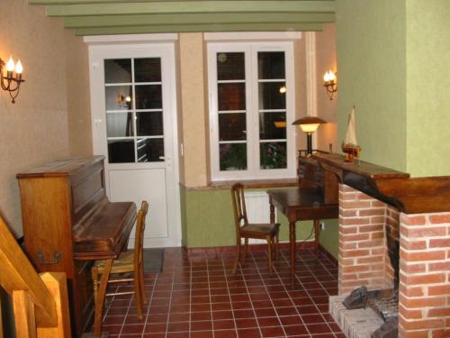 - un salon avec une cheminée, une table et un piano dans l'établissement Au Pré du Moulin, à Clamanges