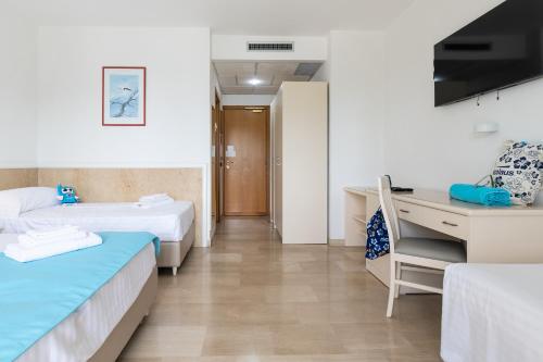 a hotel room with two beds and a desk at Nicolaus Club La Giurlita in Ugento