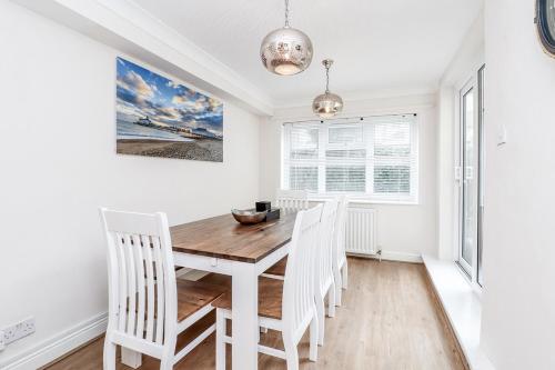 a dining room with a wooden table and white chairs at 3 Queens Gardens Sea View Apartment in Eastbourne
