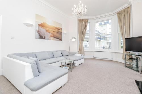 a white living room with a couch and a tv at 3 Queens Gardens Sea View Apartment in Eastbourne
