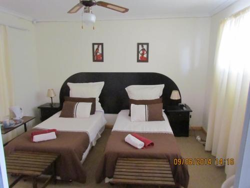 a bedroom with two beds and a ceiling fan at Blue Horizon Bay Guest House in Van Stadensriviermond