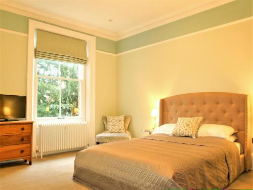 a bedroom with a bed and a window and a chair at Torrington Hall in St. Albans