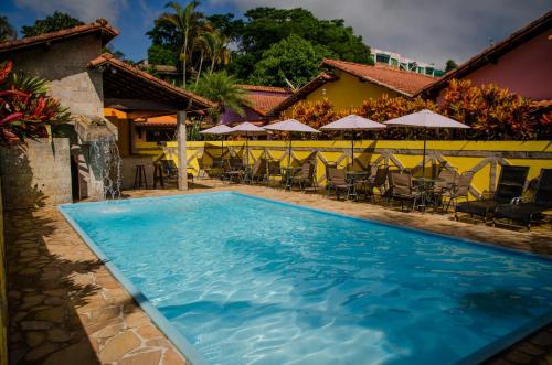 una piscina en un hotel con sillas y sombrillas en Pousada Lapônia, en Penedo