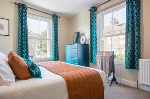 a bedroom with a bed with blue curtains and a window at Spencer House in York