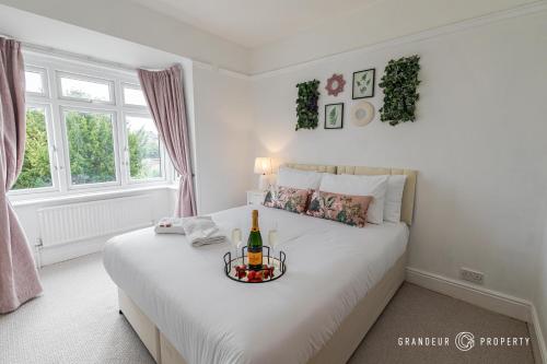 a bedroom with a white bed with a bottle of wine on it at Beautiful and Stylish 3Bedroom Flat with Parking - Beaufort Heights in Iford