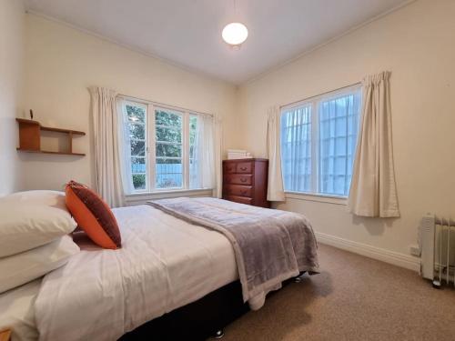 a bedroom with a bed and two windows at Country Garden Oasis with Parking and Wi-Fi in Taupaki